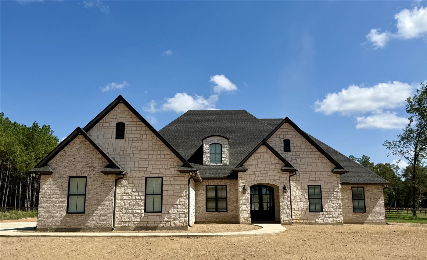 Finished custom stone and brick home with black windows built in Northwest Louisiana