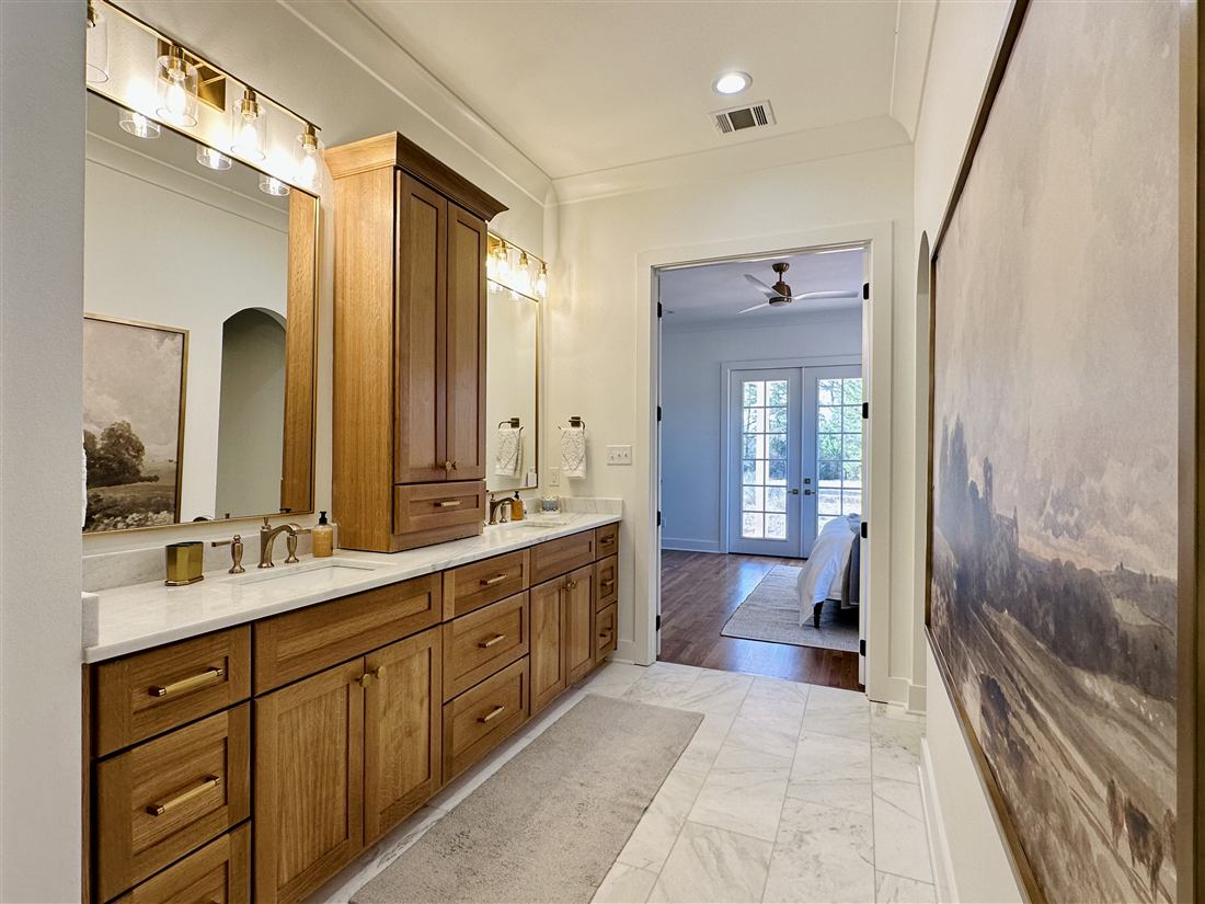 Master bathroom with white oak double vanity, marble floors and brass fixtures